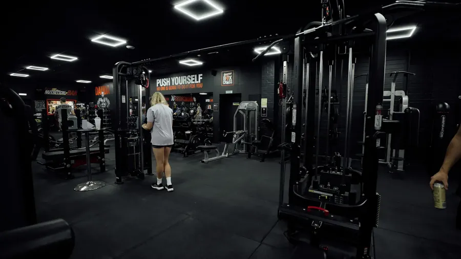 A woman training on the cable station on the main gym floor at BoxCross UK, Wisbech