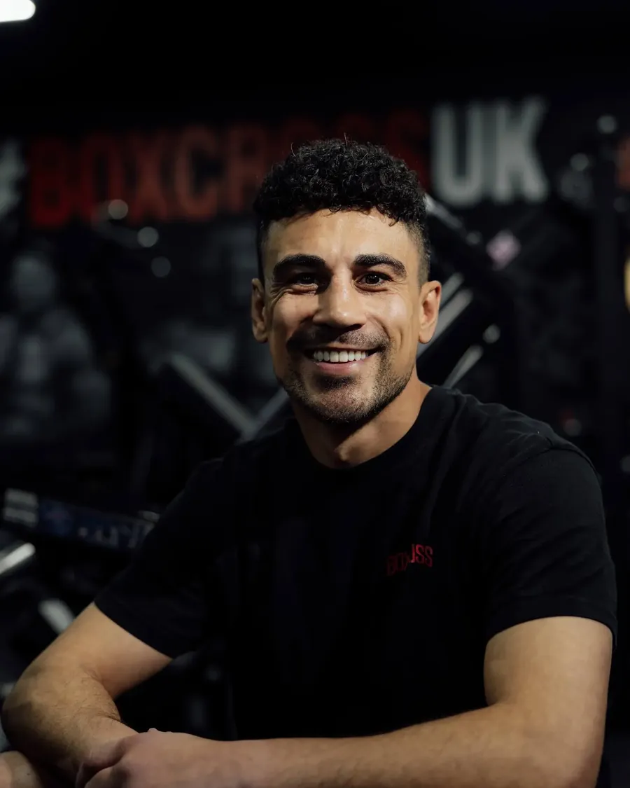 Jordan Gill, professional boxer and personal trainer in Wisbech, smiling in front of the BoxCross UK mural
